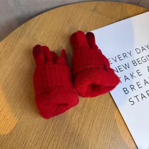 Dettaglio di guanti in maglia rossa con punta delle dita touchscreen su tavolo in legno