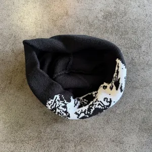 Detail van zwarte gebreide muts met wit jacquard patroon op grijze achtergrond