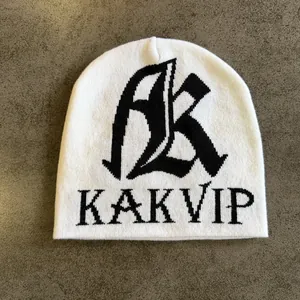 Detaillierte Strickstruktur einer weißen Beanie mit schwarzem gotischem AK-Buchstaben