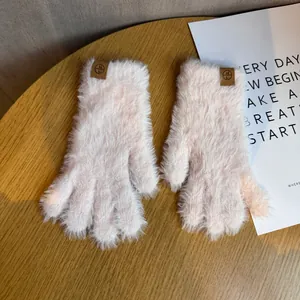 Détail de gants d'hiver en peluche rose avec étiquette en cuir sur une table en bois