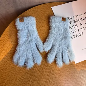 Gants d'hiver en peluche bleu clair avec écusson en cuir sur fond de bois