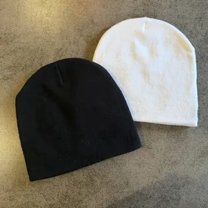 Close-up of black and white knit beanies showing the fine knit texture and soft material