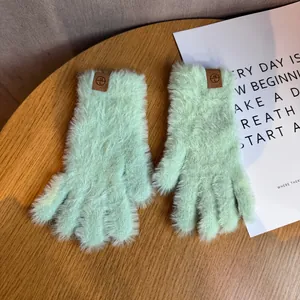 Détail de gants tactiles en peluche vert clair avec fausse fourrure et logo H L en cuir