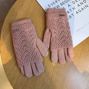 Dettaglio guanti in maglia rosa touch con motivo traforato su un tavolo di legno