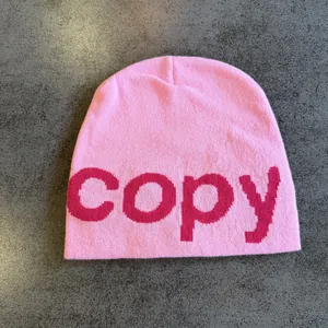 Close-up of pink knitted beanie featuring woven copy lettering with premium texture