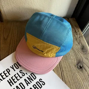 Detail of color-block five-panel mesh cap with blue mesh and yellow branded logo panel