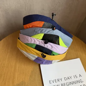 Detail view of multicolored mesh five-panel hats with adjustable toggles on wooden table