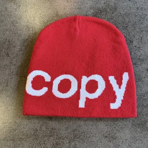 Detail of red knitted beanie featuring white copy text jacquard and warm ribbed texture