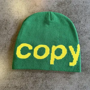 Detailed macro view of green knit beanie with yellow jacquard copy text on dark stone