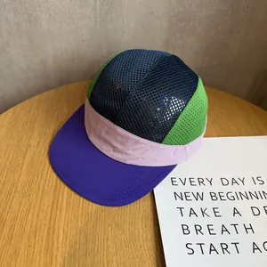 Top view of multi-color five-panel camp hat with breathable mesh and flat brim on wood table