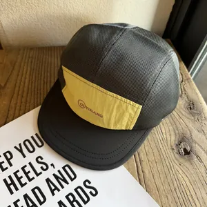 Detail of breathable mesh panels and yellow fabric on a five-panel baseball camping cap