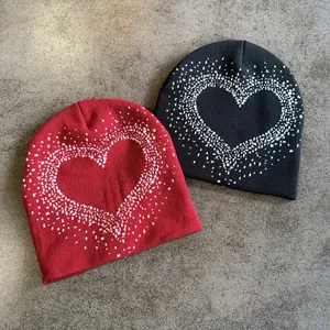 Black and red knitted beanie hats with white pixel heart patterns on a grey background