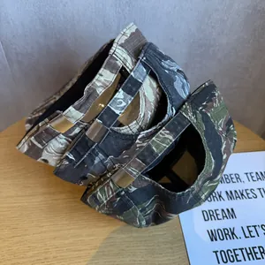 Three camouflage baseball caps with adjustable metal buckles on a rustic wooden table