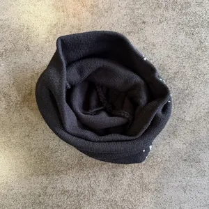 Close-up detail of black knitted beanie showing fabric texture and fine white patterns