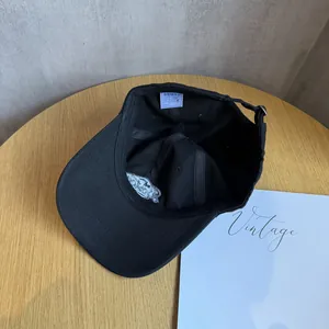 Internal view of black cotton baseball cap showing white wash label and silver logo embroidery