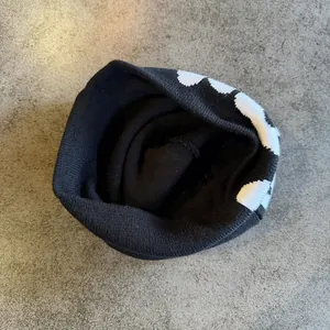 Detailed close-up showing the fine knit texture and white star pattern of this black beanie