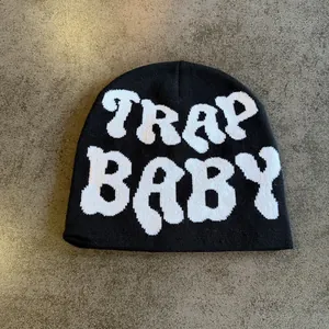 Close-up of black knit beanie featuring white TRAP BABY jacquard lettering detail