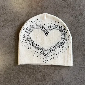 Close-up of cream knitted beanie featuring a large black pixelated heart pattern
