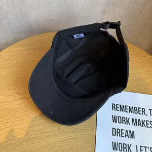Detail view of the interior seams and adjustable strap of a black cotton camper cap