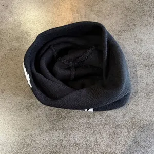 Detail of black knit beanie featuring white jacquard horse pattern and ribbed texture