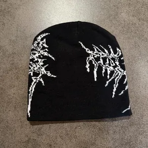 Détail d'un bonnet street style avec motif jacquard blanc sur maille noire