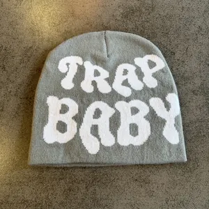 Detail of gray knitted beanie with white Trap Baby jacquard text in streetwear style