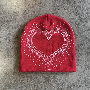Close-up of red knitted beanie featuring a white pixelated heart pattern detail