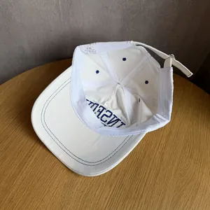Detail view showing 100% cotton material and reinforced stitching of white baseball cap