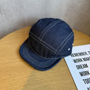 Detailed shot of dark blue denim camper hat with white stitching and metal eyelets