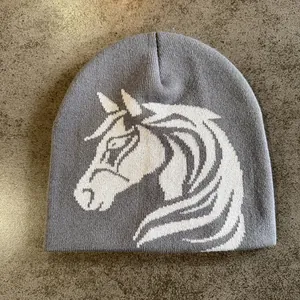 Close-up of the grey knitted beanie featuring a white horse jacquard pattern and texture
