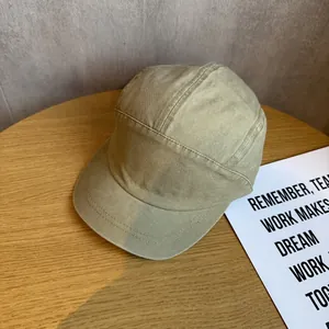 Detail of khaki 5-panel short brim baseball cap on a wooden table with aesthetic prop