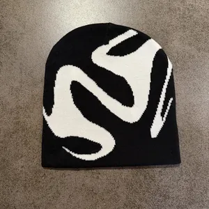 Flat lay of black and white knitted beanie with abstract jacquard street style pattern
