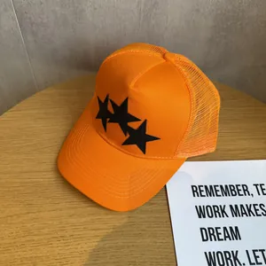 Detailed macro view of orange trucker hat with black stars and breathable mesh texture