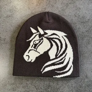 Close-up detail of knitted brown beanie featuring a white horse jacquard pattern