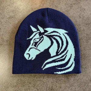 Detail of navy blue knitted beanie featuring a light blue horse pattern jacquard