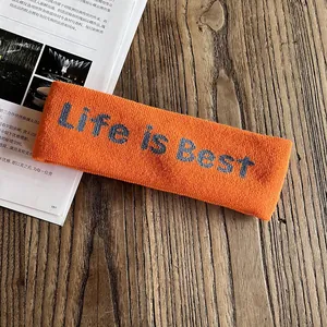 Détail du bandeau de yoga en tricot orange avec lettrage Life is Best sur bois