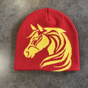 Detail of red knitted beanie featuring a yellow jacquard horse head pattern for winter
