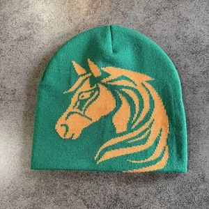 Detail of green knitted beanie with orange horse head jacquard texture and pattern