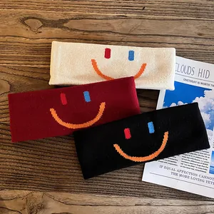 Détail de bandeaux de sport tricotés avec broderie smiley en noir, rouge et beige crème