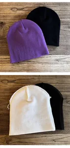 Detail shot of purple, black, and white knitted beanies on a rustic wooden background