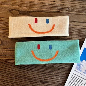 Bandeaux de sport tricotés crème et vert menthe avec motifs smiley sur fond en bois