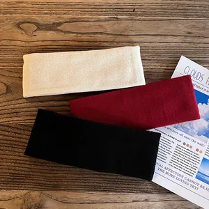 Trois bandeaux de sport larges en crème, bordeaux et noir sur une texture de bois