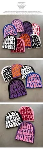 Detail of knitted jacquard beanie featuring bold 'ALL WE NEED IS MONEY' text in acrylic fabric