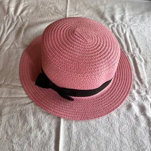 Detaillierte Draufsicht auf rosa Strohhut mit flacher Krone und schwarzer Schleife
