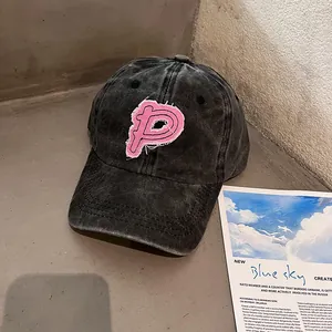 Detail der gewaschenen schwarzen Baseballkappe mit rosa Fransen-Patch und P-Stickerei