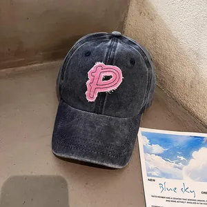 Nahaufnahme der verwaschenen Denim-Basecap mit besticktem rosa P-Patch-Detail