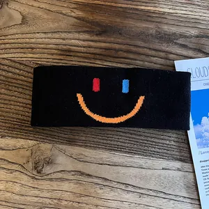 Gros plan du bandeau de sport noir avec visage souriant brodé sur une surface en bois