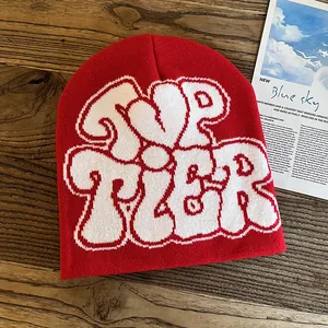 Detailed close-up of red knit beanie featuring white TOP TIER jacquard on wood surface