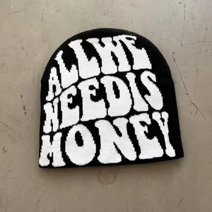 Close-up of black knit beanie with white ALL WE NEED IS HONEY jacquard lettering
