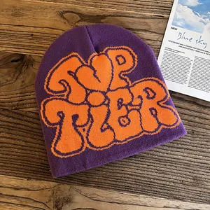 Detail of purple knitted beanie with bold orange TOP TIER lettering on wood background